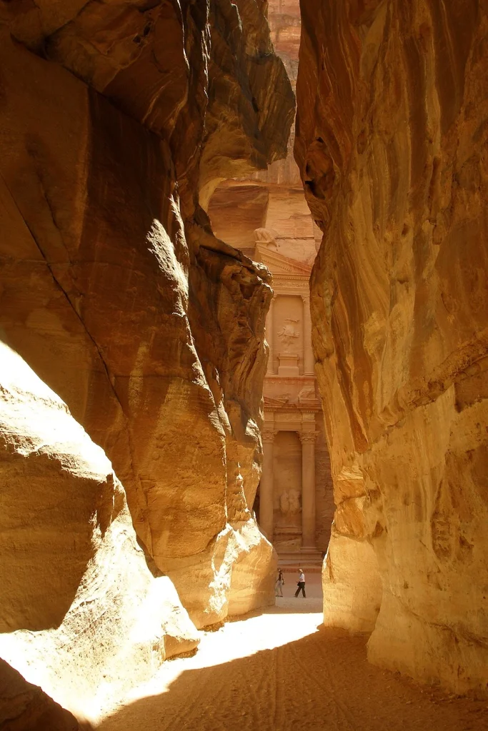 A narrow sandstone passage in the Siq with a visitor in the distance